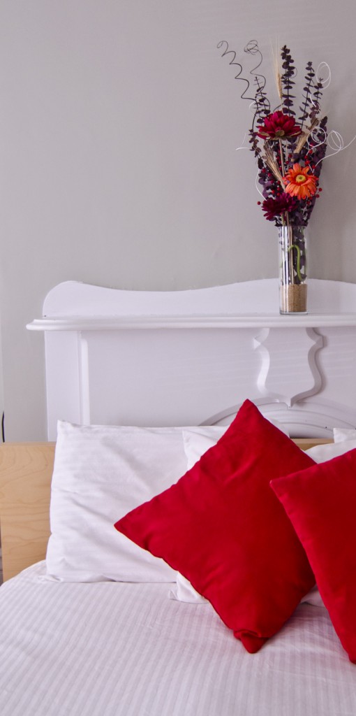 White linens, red flowers and pillows
